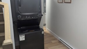 A compact kitchen with a built-in oven and microwave, a wooden staircase, and a hallway with framed artwork. - Cozy suite in a serene area (Magnetic Hill) near Casino in Moncton,NB (Moncton)