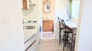 A narrow kitchen with wooden cabinets, a stove, and a dining area with a table and chairs. - newly renovated studio is on the second floor. Pet friendly  and seven minute walk to the beach<br>- FREE parking<br>-ACs<br>- Pet friendly<br>- Queen bed<br>- Fast wifi<br>- Smart TV (Old Orchard Beach)
