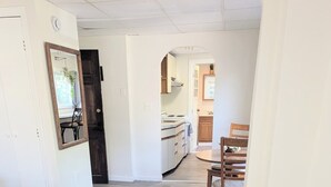 A bedroom with a floral bedspread, a wooden floor, a dining area with chairs and a table, and a kitchen visible through an archway. - newly renovated studio is on the second floor. Pet friendly  and seven minute walk to the beach<br>- FREE parking<br>-ACs<br>- Pet friendly<br>- Queen bed<br>- Fast wifi<br>- Smart TV (Old Orchard Beach)