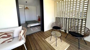 A balcony with a wooden floor, a sofa, two chairs, and a decorative lattice partition.