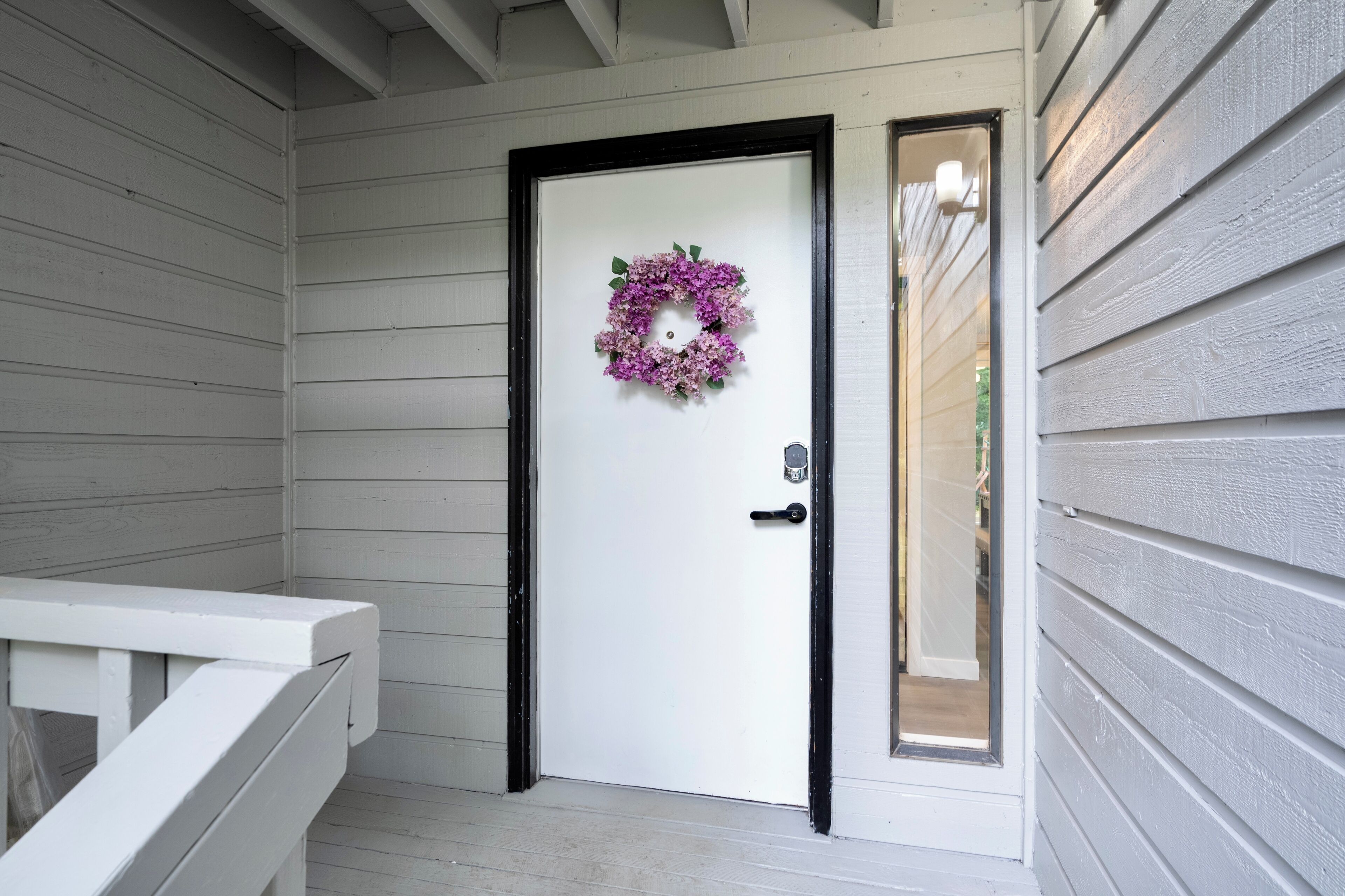 A white door with a black frame and a purple floral wreath.
