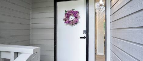 A white door with a black frame and a purple floral wreath.