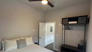A bedroom with a bed, a ceiling fan, a wardrobe, and a shelf unit. - Downtown Minimalist Apartment (International Falls)