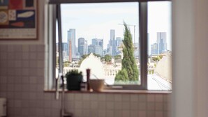 A kitchen with a window view of a city skyline.