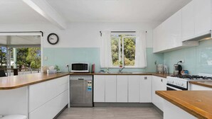 A modern kitchen with white cabinets, a microwave, a dishwasher, and a window with curtains.