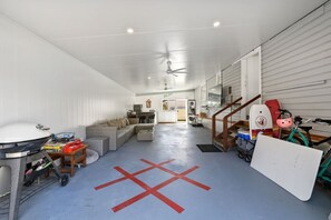 A spacious indoor area with a ceiling fan, a couch, a dining table, and a kitchen in the background. - Pumicestone Porch – 4BR Pet-Friendly, Walk to Bongaree Jetty (City of Moreton Bay)