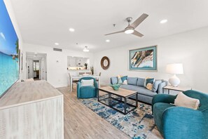 A modern living room with a sofa, armchair, coffee table, and a ceiling fan.