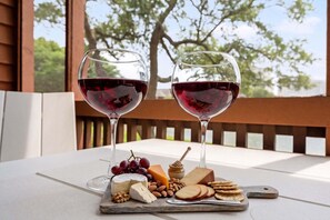 Two wine glasses on a table with a cheese board, grapes, and nuts.