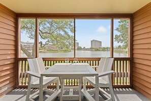 A balcony with a table and chairs, a view of a body of water, and buildings in the background.