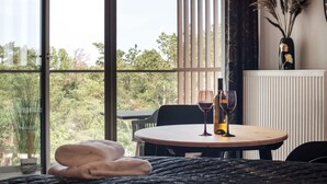 Ein Zimmer mit einem runden Tisch, zwei Weingläsern und einer Vase mit Trockenpflanzen.