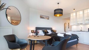 Ein modernes Schlafzimmer mit Bett, Nachttischen und einem Essbereich mit Stühlen.