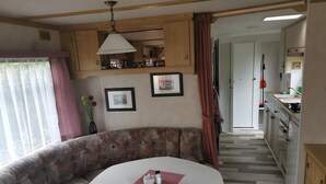 Ett mysigt vardagsrum med en soffa, ett bord och ett kök i bakgrunden.