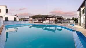 A swimming pool with lounge chairs and a covered seating area, surrounded by buildings and trees. - Barammak-i Pension, Muchangpo, Boryeong (Boryeong)
