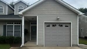 A single-story house with a grey garage door, a small porch, and a number '29456' on the wall.