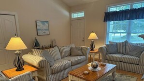 A cozy living room with striped sofas, a wooden coffee table, and two lamps.