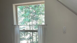 Una habitación con una sola ventana, paredes blancas y un radiador blanco.