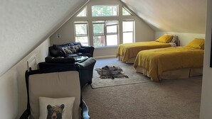 Un dormitorio acogedor en el ático con cama entrepiso, un sofá y una silla.