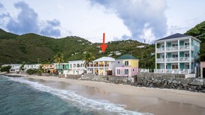 Une propriété située en bord de mer, avec un bâtiment à deux étages, un balcon et une vue sur l’océan.