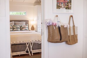 Un dormitorio con cama, almohadas, una mesita de noche, una lámpara y un perchero en la pared.