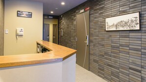 A reception area with a wooden counter, a framed picture on the wall, and a door with a sign.
