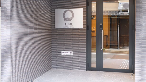 A modern building entrance with a signboard displaying the logo and name 'JP Inn'.
