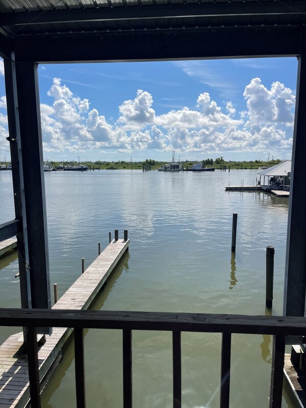 A view from a covered dock area overlooking calm water with boats and docks in the distance.