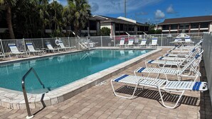 Une piscine avec des chaises longues et un espace délimité par une clôture.