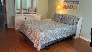 Une chambre à coucher comprenant un lit, une commode, un miroir et une œuvre d’art accrochée au mur.