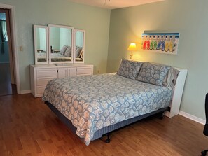 Una camera da letto con un letto, una cassettiera, uno specchio e un'opera d'arte appesa al muro.