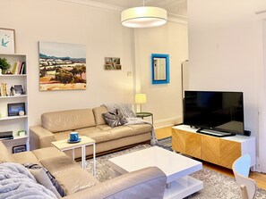 A modern living room with a sofa, coffee table, TV, and artwork on the wall.