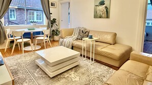 Sala de estar com sofá, mesa de centro e área de jantar com cadeiras.