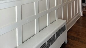 Ein Flur mit einer Reihe gerahmter Bilder an der Wand und einer weißen Bank.