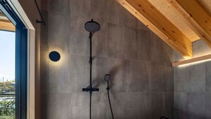 A modern bathroom with a wooden ceiling, a built-in bathtub, and a shower unit.