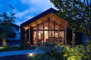 Una casa moderna con un ampio portico aperto, travi in legno e interni ben illuminati.