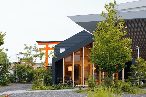Un edificio moderno con un grande torii arancione, travi in legno e porte in vetro.