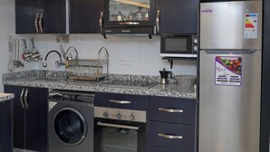 A modern kitchen with a built-in washing machine, stainless steel refrigerator, and granite countertops.
