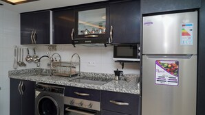 A modern kitchen with dark cabinets, stainless steel appliances, and a granite countertop.