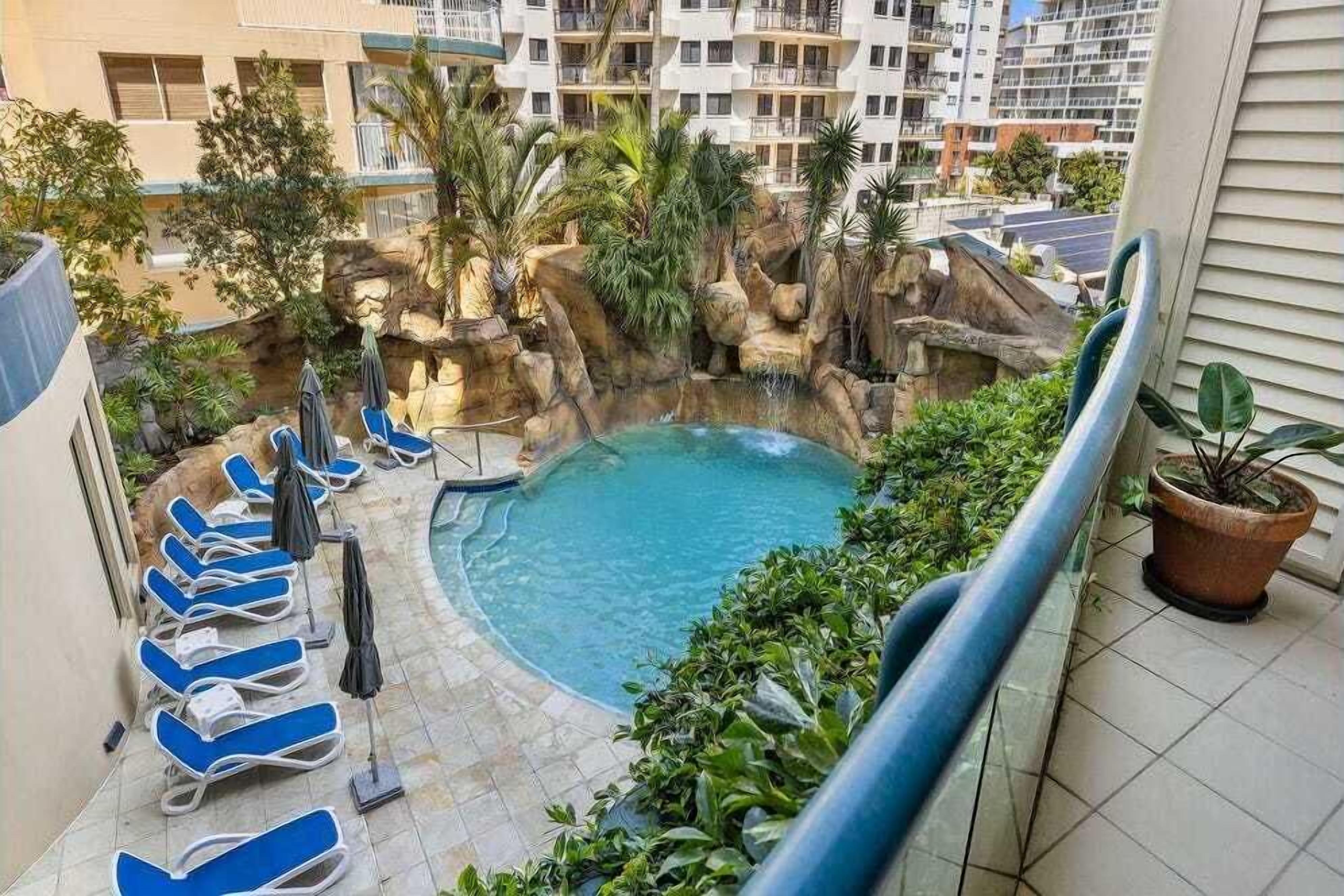 Un área de piscina con sillones de descanso y una cascada.