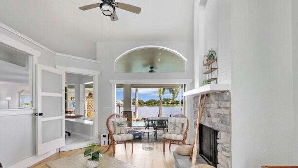 A spacious living room with a fireplace, a dining area, and a view of a pool.