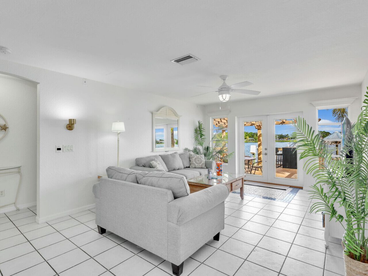 A modern living room with a grey sofa, a coffee table, and a view of the outdoors through large windows.