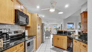 A modern kitchen with wooden cabinets, stainless steel appliances, and a tiled floor.