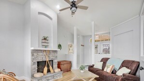 A living room with a stone fireplace, a brown leather sofa, and a wooden coffee table.