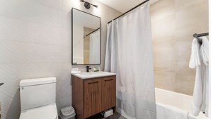 Une salle de bain moderne équipée de toilettes, d’un meuble-lavabo et d’une baignoire.