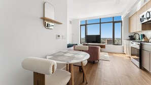 Une cuisine moderne dotée d’une grande fenêtre, un coin repas avec une table et des chaises, et une vue sur la ville.