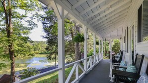 A covered porch with a view of a pond and trees. - Heatherbell, A Lakeside Retreat (Saylorsburg)