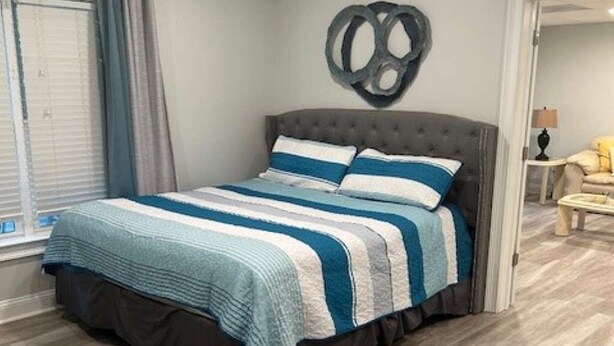 A bedroom with a bed, a window with curtains, a wall decoration, and a door leading to another room. - Cozy Quiet Whole Apartment Haven for Rent (Grayson)