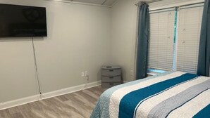 A bedroom with a bed, a television mounted on the wall, a window with curtains, and a small dresser. - Cozy Quiet Whole Apartment Haven for Rent (Grayson)