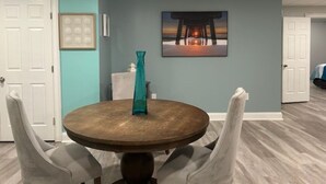 A dining area with a round table, four chairs, a teal vase, and a painting on the wall. - Cozy Quiet Whole Apartment Haven for Rent (Grayson)