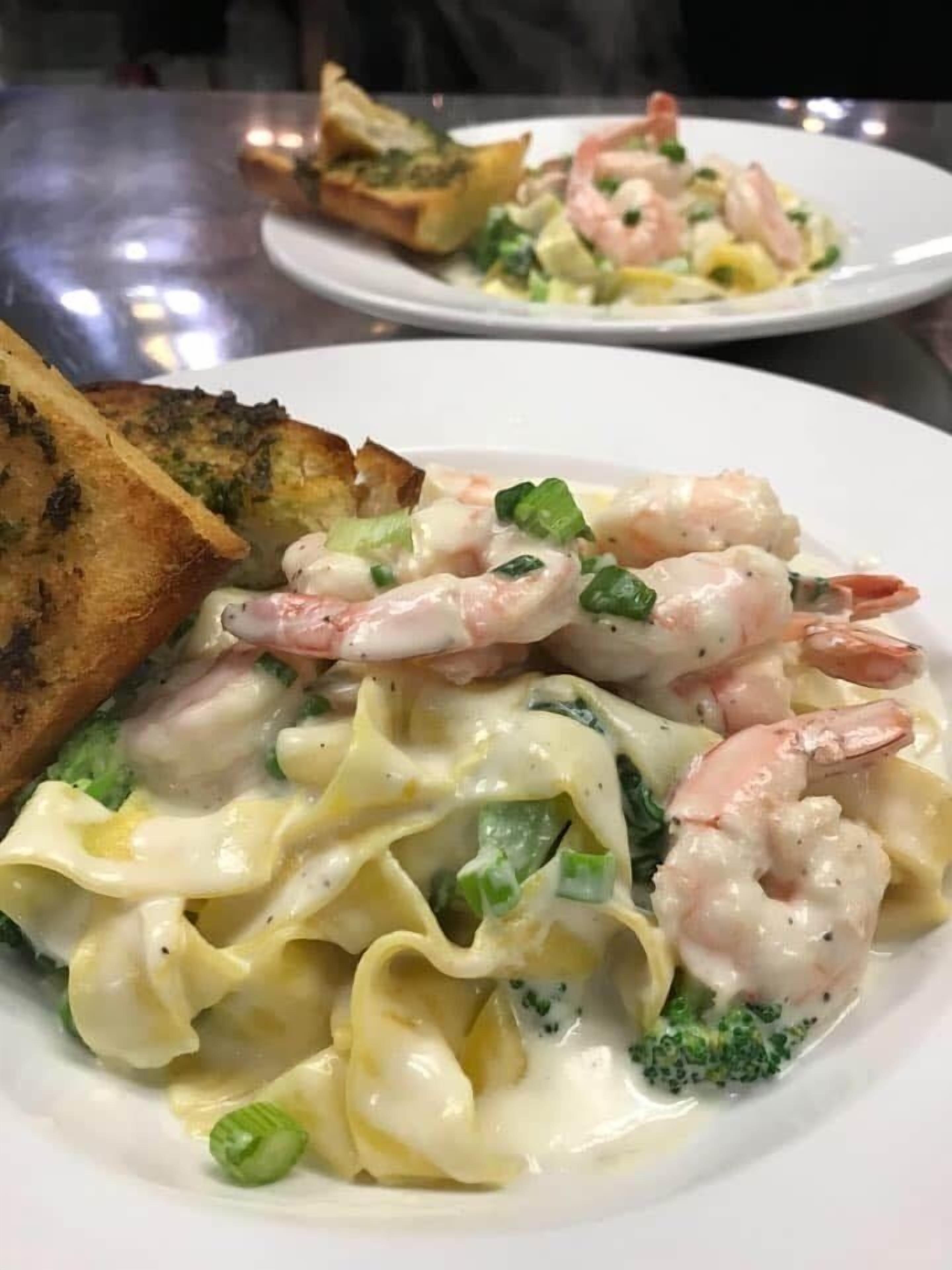 Une assiette de pâtes aux crevettes et aux brocolis, accompagnée de pain grillé.