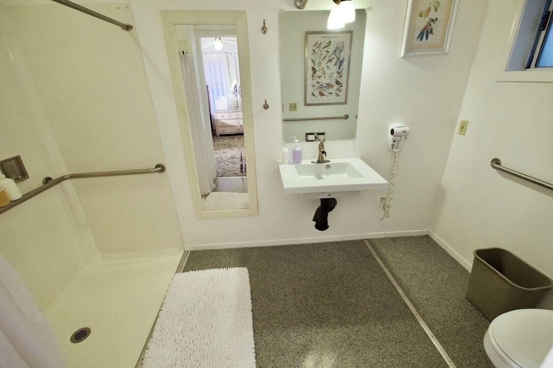 A bathroom with a white sink, a mirror, a shower, and a toilet.